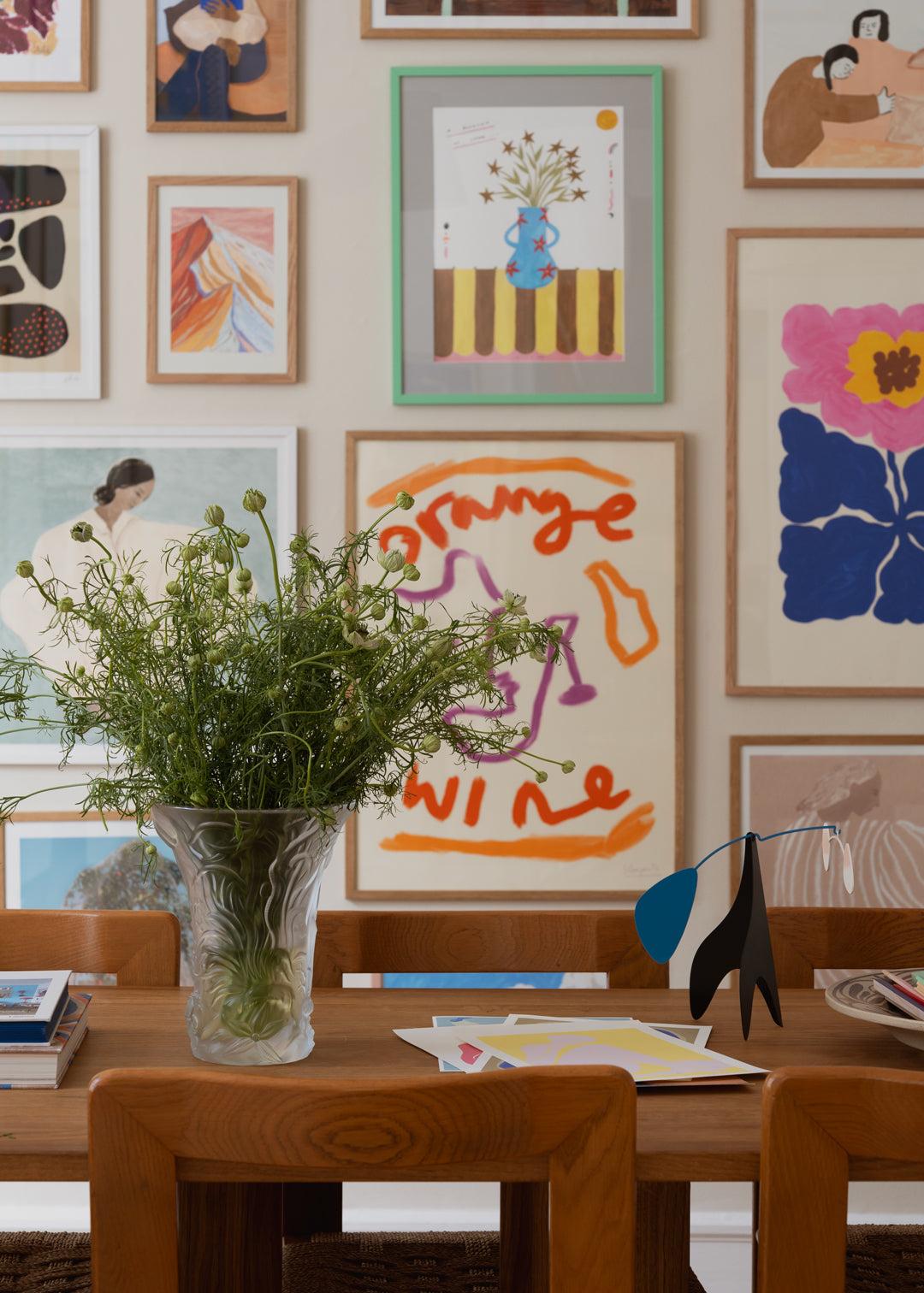 Dining room with a wooden table, vase of flowers, and colorful abstract art on the wall.